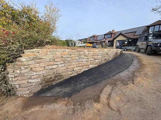 Natural stone retaining wall and new tarmac path